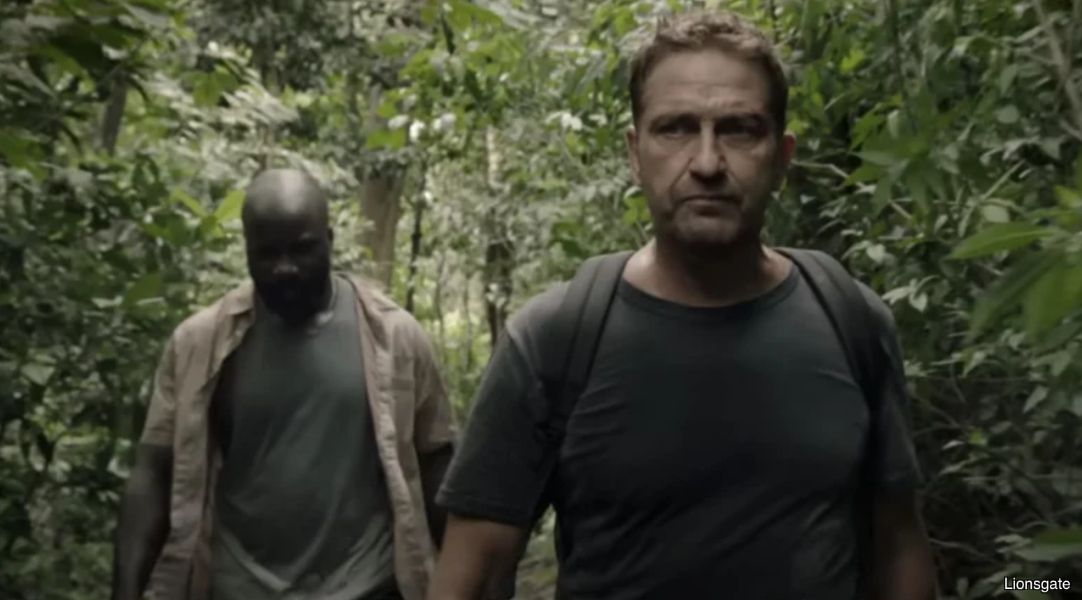 Promotional image from Gerard Butler's Plane that shows two men walking through jungle; Lionsgate image credit in lower right-hand corner